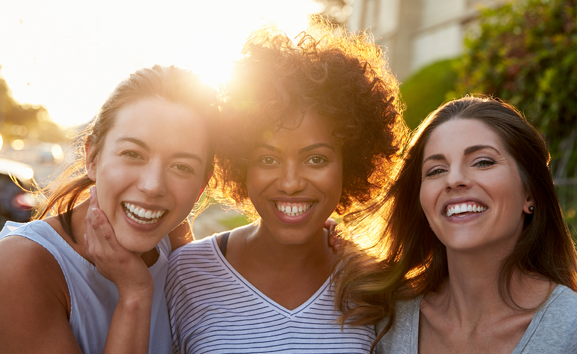 Three breast cancer survivors smiling together.